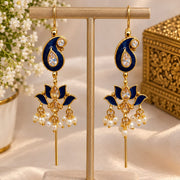 A pair of gold-plated Indian Kalka earrings with navy blue enamel, clear teardrop crystals, and white pearl bead drops, displayed on a beige jewelry stand.